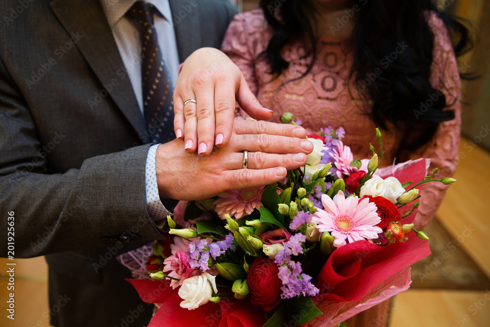 Hands of the groom and bride with rings and bridal bouquet Hands of the groom and bride with rings and bridal bouquet