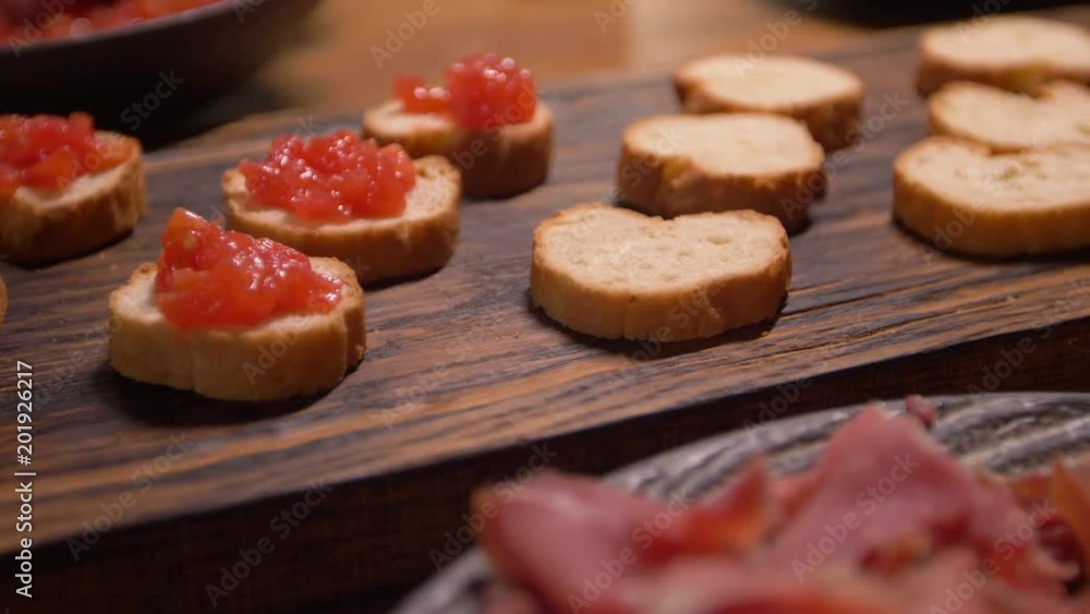 Preparation of Spanish tapas. Putting some finely chopped tomatoes on slices of baguette. Preparation of Spanish tapas. Putting some finely chopped tomatoes on slices of baguette.