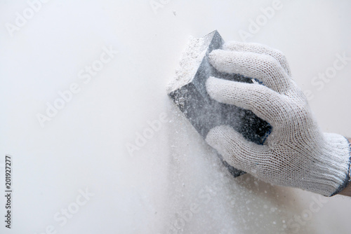 Hand smoothing out wall with sandpaper photo