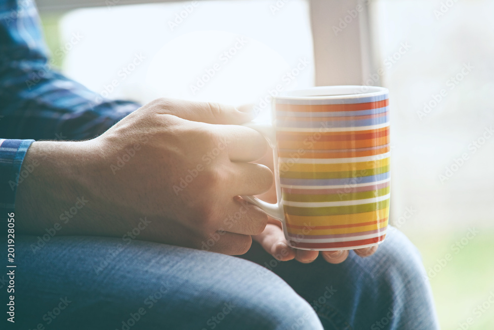 man sitting near window with cup of morning coffee or tea man sitting near window with cup of morning coffee or tea