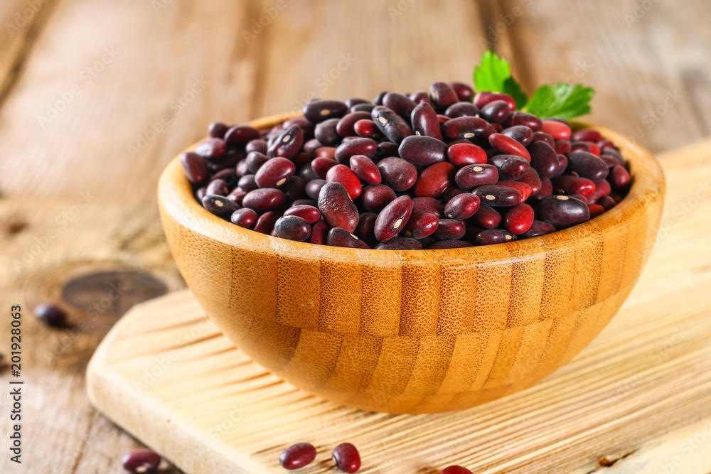 Red raw beans with greens on a wooden table. Red raw beans with greens on a wooden table.