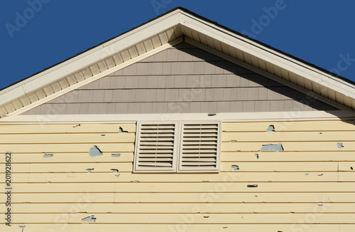 Holes in exterior siding in home from damage by hail storm 