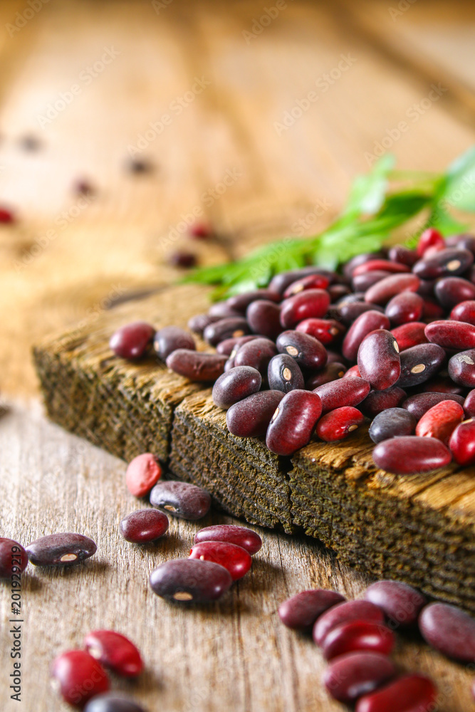 Red raw beans with greens on a wooden table. Red raw beans with greens on a wooden table.
