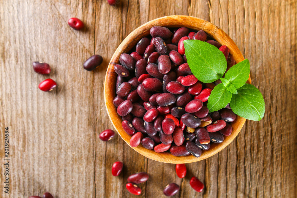 Red raw beans with greens on a wooden table. Red raw beans with greens on a wooden table.