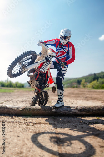 Hard enduro motorcycle rider crossing logs on an obstacle course. Extreme outdoor sports.