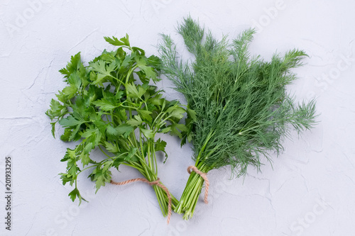 Fresh garden dill and parsley. One bunch of parsley and one bunch of dill on light background.
