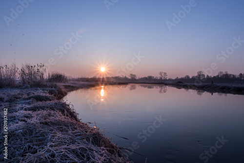 sunrise on the background of a winding wild river  its backwaters and backlit with reed promises  early spring