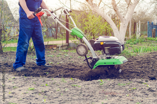 Fotografie Man working in the spring garden with tiller machine