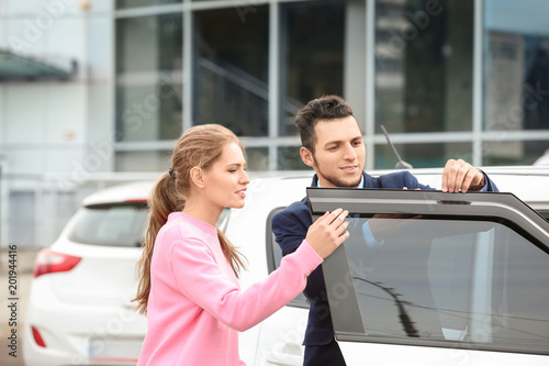 Salesman showing new car to...