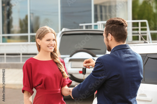Salesman giving car key to ...