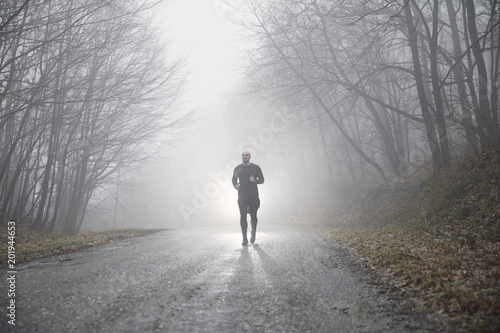 one runner jogging, outdoors mist fog, mysterious forest.