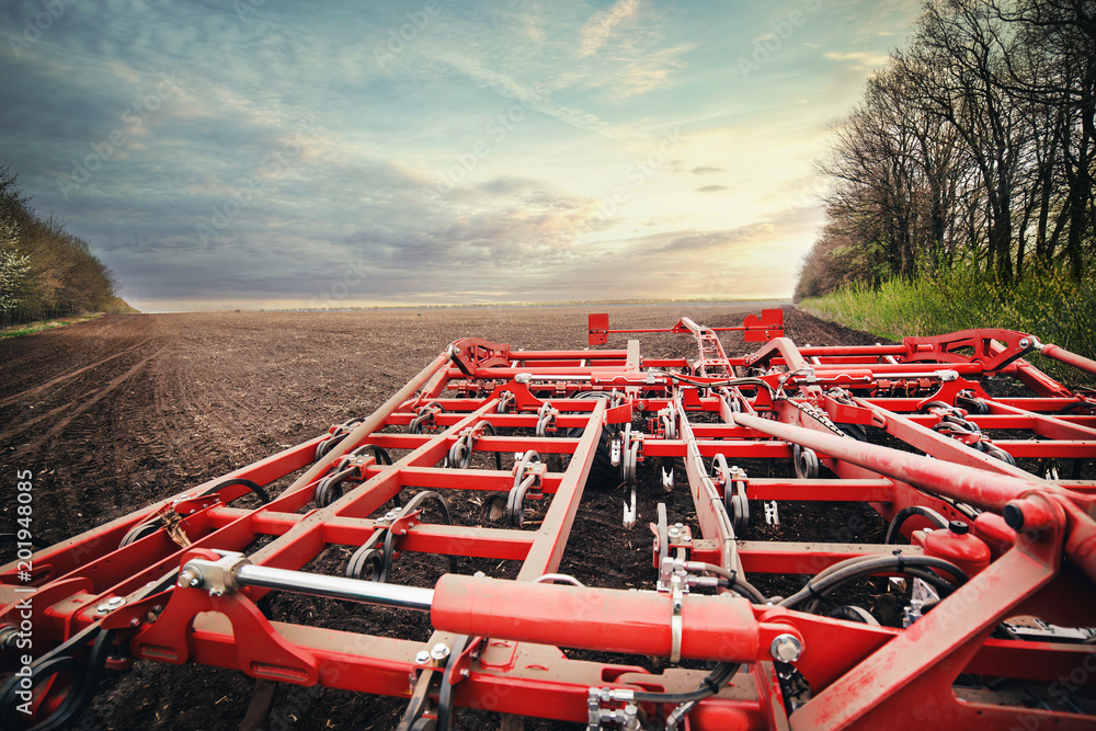roller with a harrow works on the ground at sunrise in a field in the spring