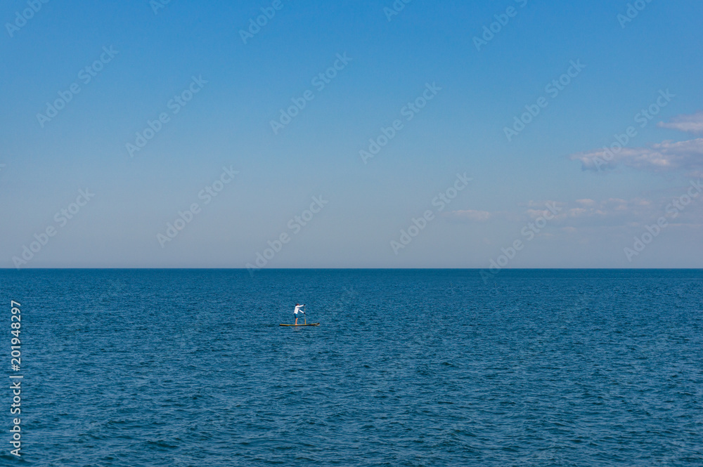 Person on paddle board, standing board in the ocean