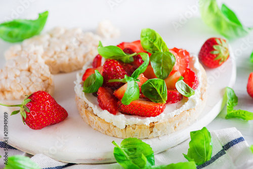 Healthy snack with crisp bread, fresh strawberries, goat cheese, and basil leaves. Easy appetizer recipe.