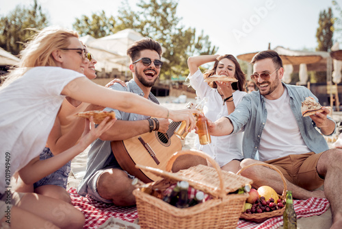Group of happy young people having a picnic on the beach © ivanko80