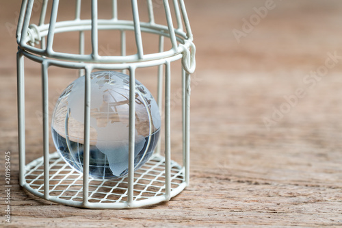 glass globe with america map inside birdcage on wooden table metaphor of limited thinking, underprotection or anti globalization