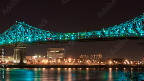 Leinwand Poster Long exposure shot of Jacques Cartier Bridge Illumination in Montreal, reflection in water