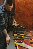 Man works in carpentry workshop. He fixes wooden handle in vice. Different tools are on workbench. Men at work. Hand work.