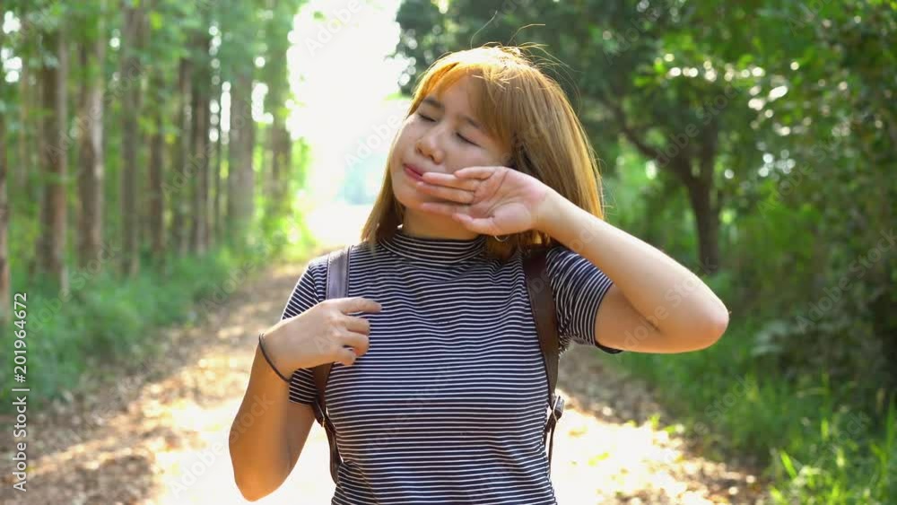 Happy young Asian woman traveler with backpack walking in forest. Hiker Asian woman with backpack walking on path in summer forest. Adventure backpacker travel people concept. Happy young Asian woman traveler with backpack walking in forest. Hiker Asian woman with backpack walking on path in summer forest. Adventure backpacker travel people concept.