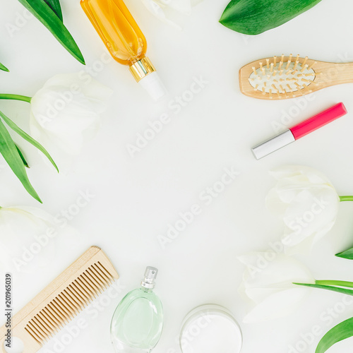 Frame with cosmetics, perfume, combs and tulips flowers on white background. Beauty blog composition. Flat lay, top view