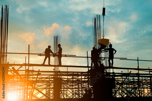 Silhouette of engineer and construction team working at site over blurred background sunset pastel for industry background with Light fair.