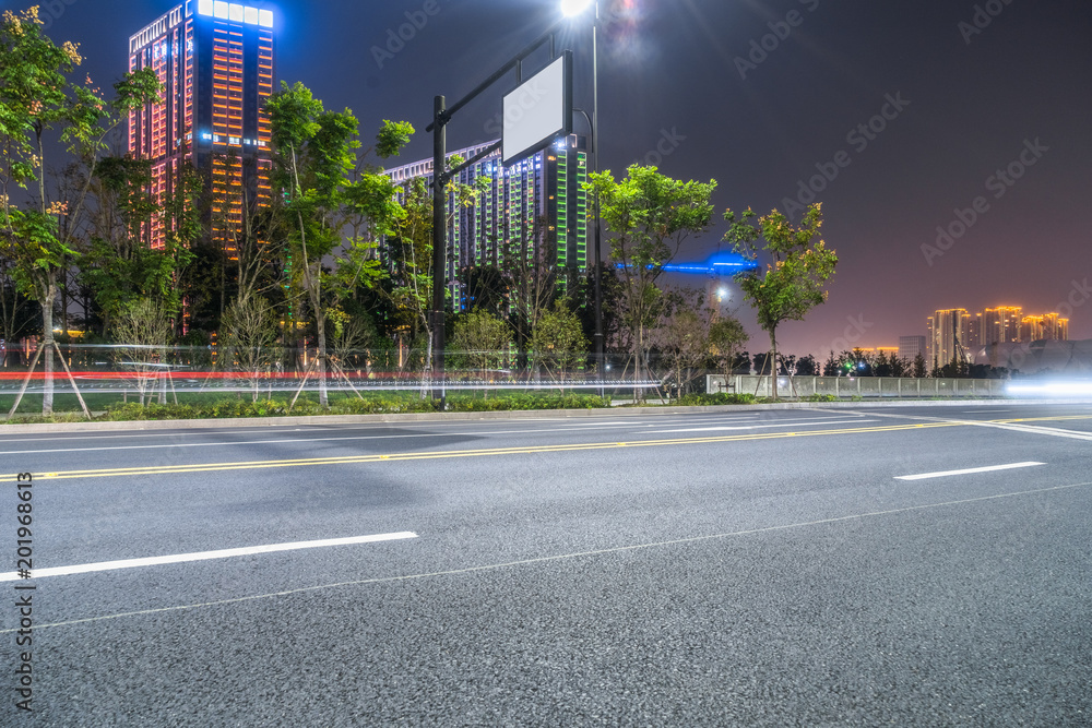 Empty asphalt road through modern at night