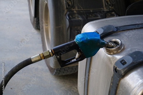 Oil dispenser is being poured into a truck tank.
