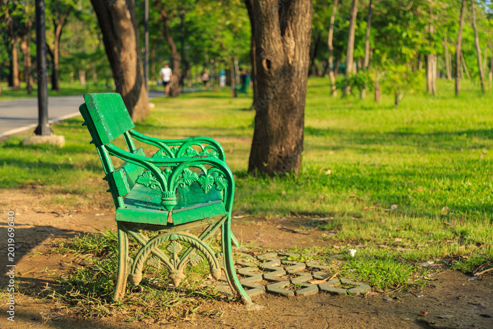 A green bench on a lawn in a park at evening. A green bench on a lawn in a park at evening.