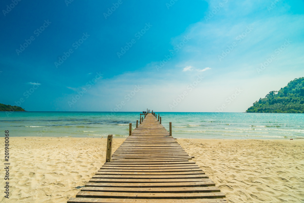 Fototapeta premium Wooden pier or bridge with tropical beach and sea in paradise island