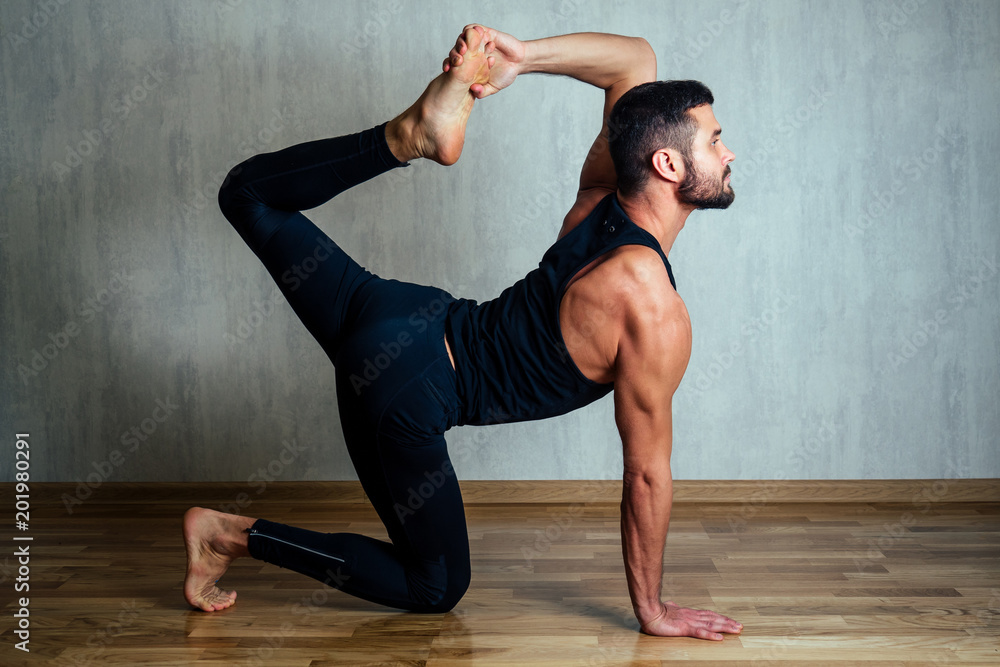 a man in dark sportswear practicing yoga on a dark background. asana on the floor on yoga mats. the concept of concentration and possession of the body a man in dark sportswear practicing yoga on a dark background. asana on the floor on yoga mats. the concept of concentration and possession of the body