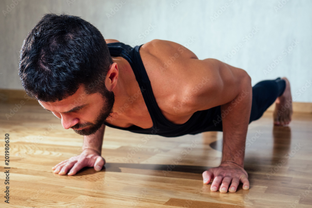 A muscular man does exercises to strengthen the muscles of the hands on the floor. push-up from the floor. concept of health promotion and beautiful body A muscular man does exercises to strengthen the muscles of the hands on the floor. push-up from the floor. concept of health promotion and beautiful body