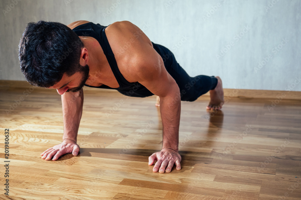 A muscular man does exercises to strengthen the muscles of the hands on the floor. push-up from the floor. concept of health promotion and beautiful body A muscular man does exercises to strengthen the muscles of the hands on the floor. push-up from the floor. concept of health promotion and beautiful body