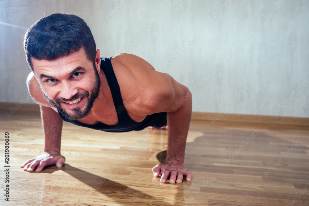 A muscular man does exercises to strengthen the muscles of the hands on the floor. push-up from the floor. concept of health promotion and beautiful body A muscular man does exercises to strengthen the muscles of the hands on the floor. push-up from the floor. concept of health promotion and beautiful body