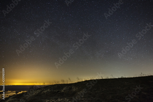 Bright stars in the night sky against the backdrop of the hills. Landscape with a long exposure.