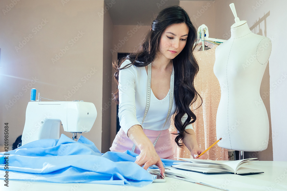 Premium Photo  Young dressmaker woman sews clothes on