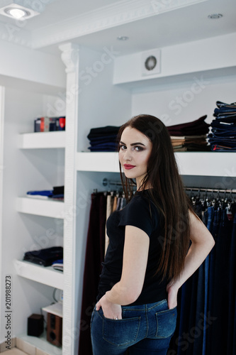 Brunette gorgeous girl in the clothing store boutique at casual clothes, black shirt and jeans.