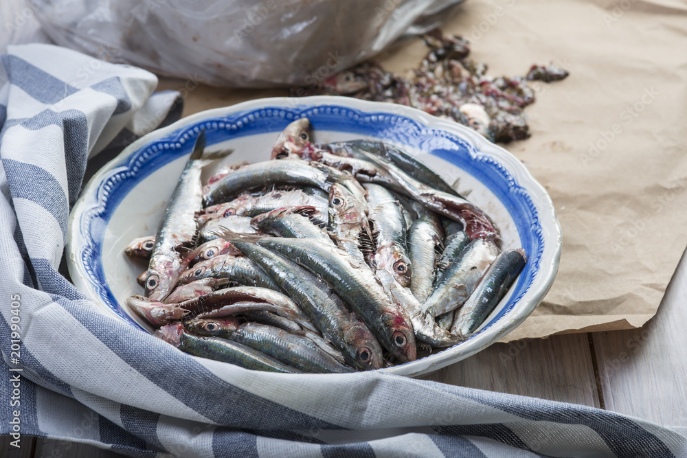 Limpiando pescado, sardinas frescas en la mesa de la cocina para la comida Limpiando pescado, sardinas frescas en la mesa de la cocina para la comida