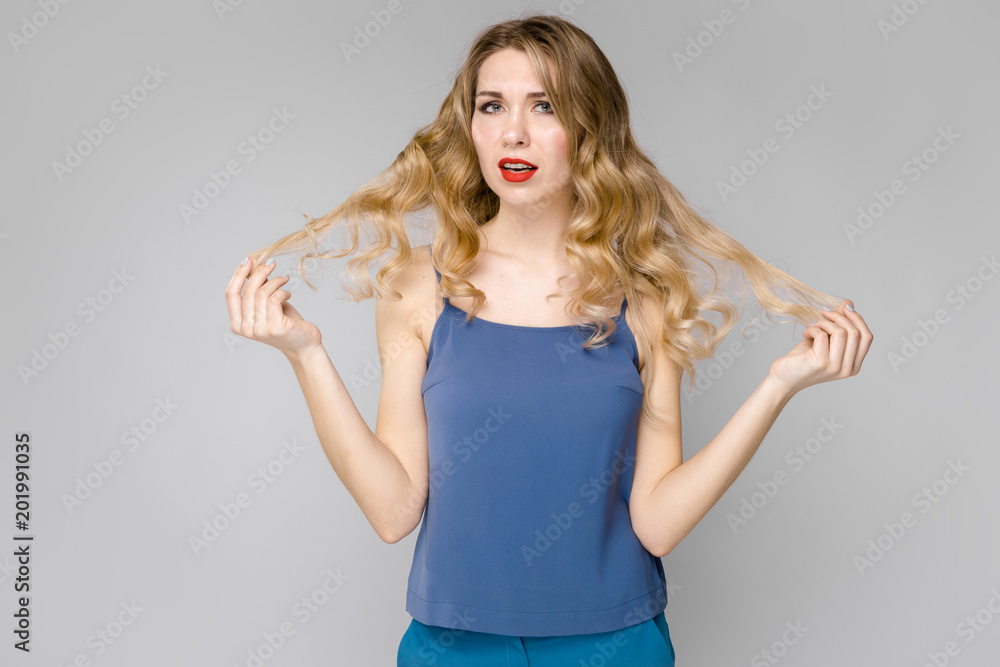 Charming young blonde astonished girl in blue clothes on gray background Charming young blonde astonished girl in blue clothes on gray background