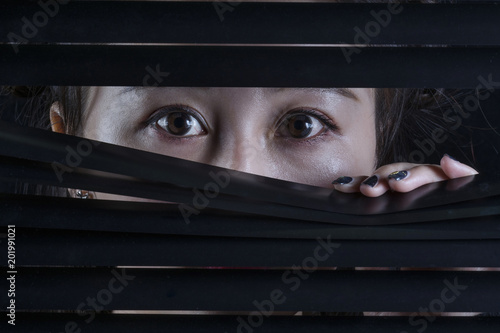 Obraz na plátně Oriental woman looking through a blind