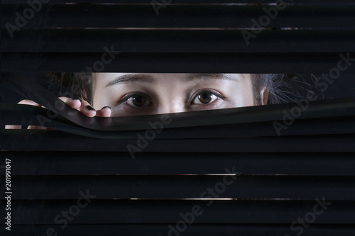 Oriental woman looking through a blind