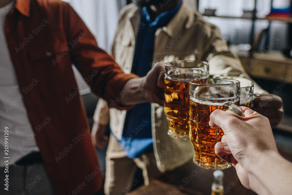 cropped shot of male friends clinking glasses of beer