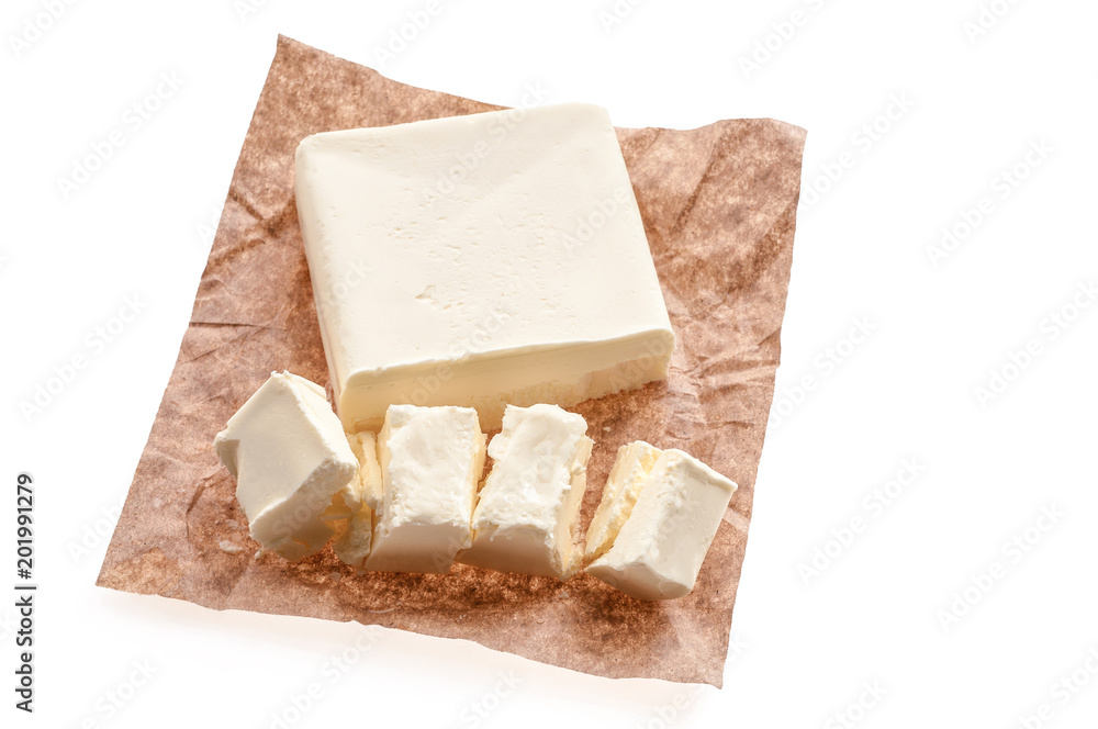 Top view of creamy piece of butter on a saucer over food paper background