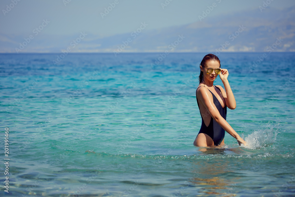 beautiful young woman in bikini bathing and splashing happily in the sea at the resort