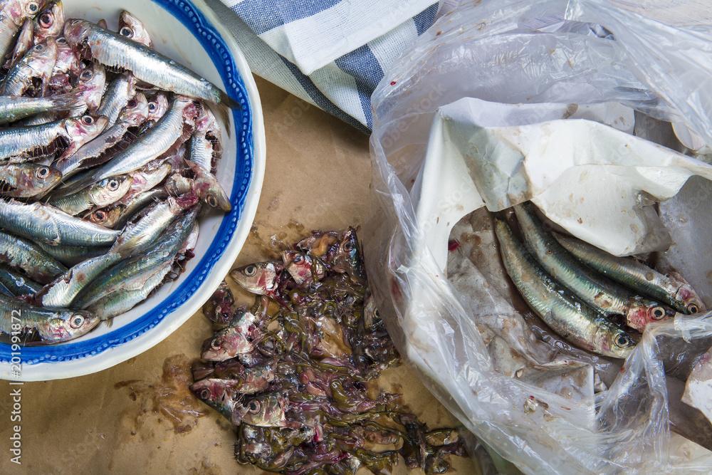 Limpiando pescado, sardinas frescas en la mesa de la cocina para la comida Limpiando pescado, sardinas frescas en la mesa de la cocina para la comida