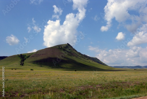 Wide steppe with yellow grass under a blue sky with white clouds Sayan mountains Siberia Russia