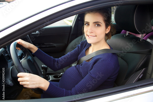 Beautiful pregnant woman sitting in car driving smiling looking camera