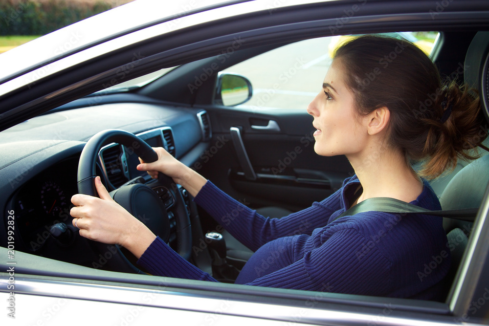 Pregnant woman driving car holding wheel Pregnant woman driving car holding wheel