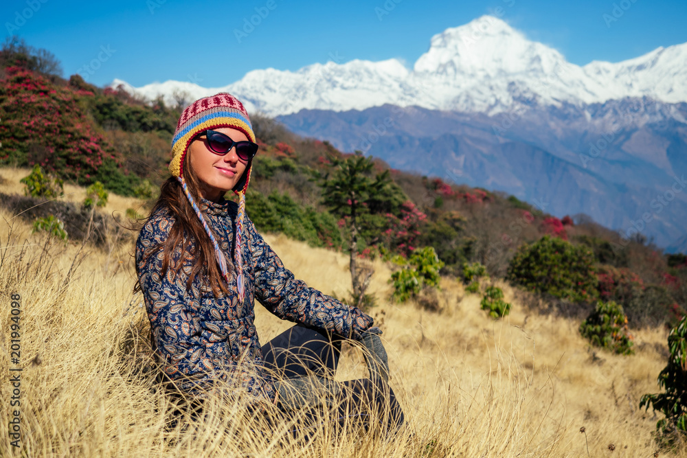 Naklejka premium Smiling young beautiful and active woman in trekking in the mountains. the concept of active recreation and tourism in the mountains. trekking in Nepal Himalayas