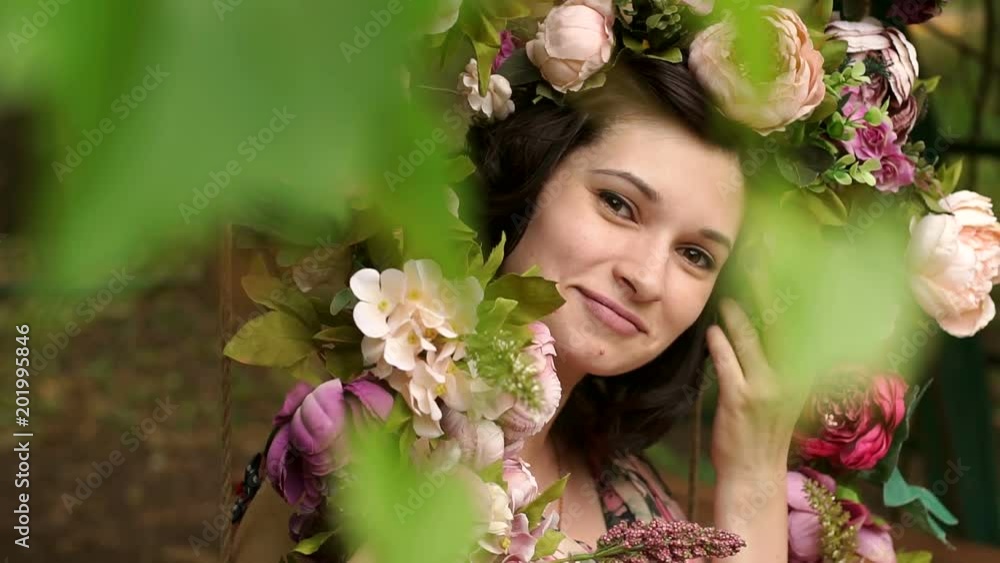 A young pregnant girl sitting on a swing decorated with flowers in the Park at sunset. Happy pregnant girl in a flowered dress sitting on a swing. The concept of a new life. Slow motion. A young pregnant girl sitting on a swing decorated with flowers in the Park at sunset. Happy pregnant girl in a flowered dress sitting on a swing. The concept of a new life. Slow motion.