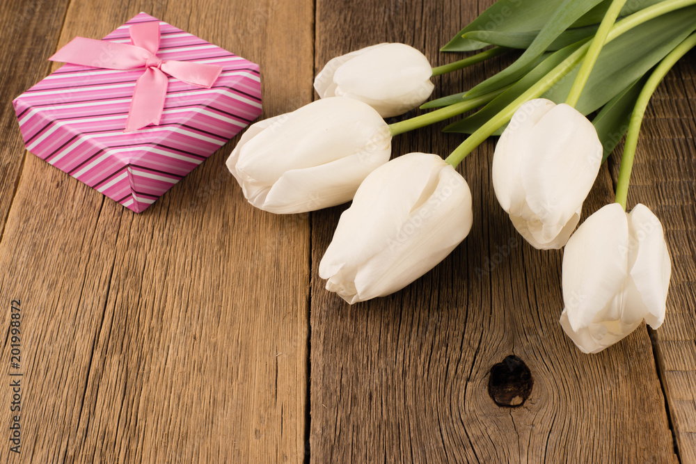 White tulips with gift on old wooden table. White tulips with gift on old wooden table.